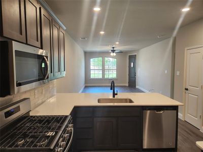 Kitchen with stainless steel appliances, sink, ceiling fan, backsplash, and hardwood / wood-style flooring