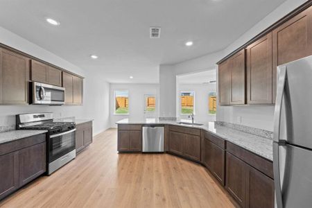 Kitchen with light wood-style floors, dark cabinets, stainless steel appliances, and kitchen peninsula