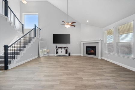 Unfurnished living room with high vaulted ceiling, light wood-type flooring, ceiling fan, and a healthy amount of sunlight