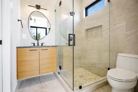 Bathroom with plenty of natural light, a shower with shower door, vanity, and toilet