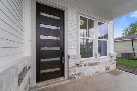 Lovely porch featuring a modern front door and elegant stone and hardie plank exterior.