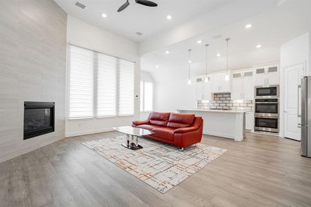 Living room featuring ceiling fan, light wood-type flooring, and a fireplace