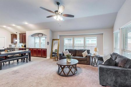 Living room featuring ceiling fan, lofted ceiling, and light colored carpet