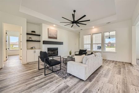 Living room with light hardwood / wood-style floors, plenty of natural light, ceiling fan, and a brick fireplace