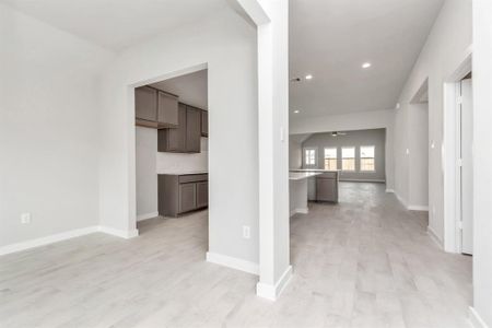 At the forefront, a large dedicated dining room. Luxurious details like premium flooring, custom paint, and expansive windows allowing an abundance of light. Sample photo of completed home with similar floor plan. As-built interior colors and selections may vary.