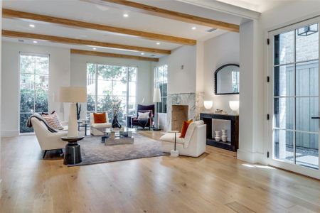 Living room featuring beamed ceiling, a premium fireplace, and light hardwood / wood-style floors