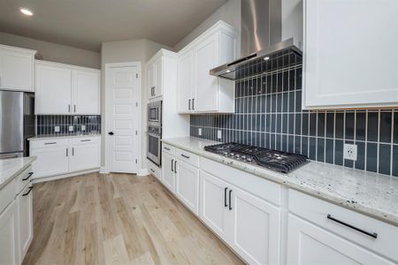 The combination of white cabinets, stainless steel appliances, and granite countertops infuses the kitchen with a bright and inviting ambiance, enhancing the sense of openness and freshness while reflecting natural light throughout the space.