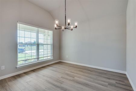 Spare room featuring hardwood / wood-style flooring, a chandelier, and vaulted ceiling