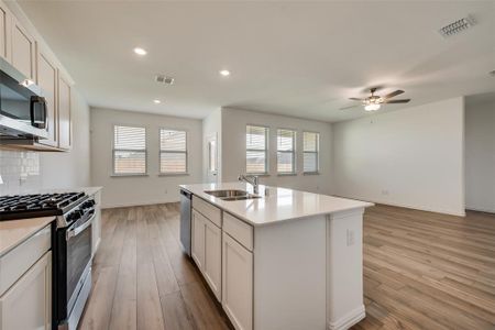 Kitchen with an island with sink, stainless steel appliances, light hardwood / wood-style floors, and backsplash