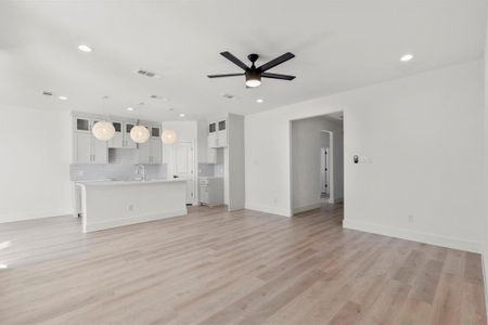 Unfurnished living room with sink, light hardwood / wood-style flooring, and ceiling fan