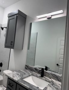 Bathroom featuring vanity, tiled shower, and toilet