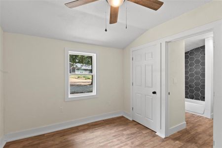 Unfurnished bedroom with hardwood / wood-style flooring, vaulted ceiling, and ceiling fan