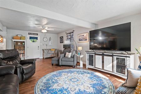 Living room with beamed ceiling, ceiling fan, and hardwood / wood-style floors