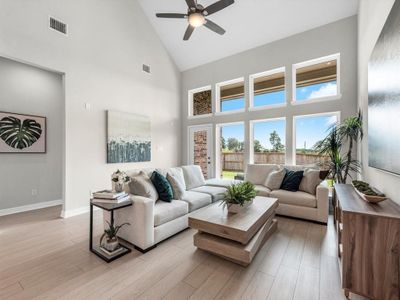 Living room with ceiling fan, light wood-type flooring, and high vaulted ceiling