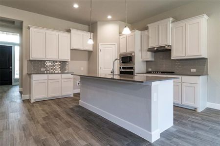 Kitchen featuring white cabinets, a center island with sink, appliances with stainless steel finishes, and dark hardwood / wood-style floors