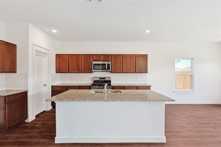 Kitchen featuring an island with sink, stainless steel appliances, dark hardwood / wood-style flooring, and decorative backsplash