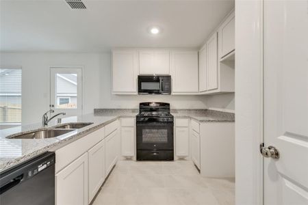 Kitchen featuring white cabinetry, sink, black appliances, and light tile patterned floors