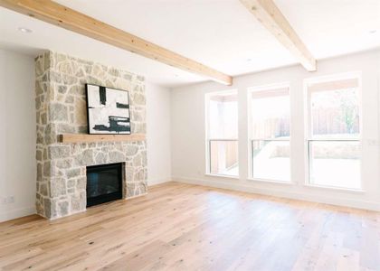 Unfurnished living room with light hardwood / wood-style floors, beamed ceiling, and a stone fireplace