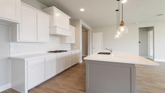 Kitchen with white cabinets, pendant lighting, sink, backsplash, and a kitchen island with sink