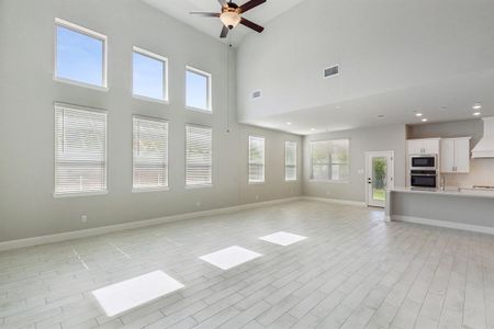 Unfurnished living room with a high ceiling, light hardwood / wood-style floors, and ceiling fan