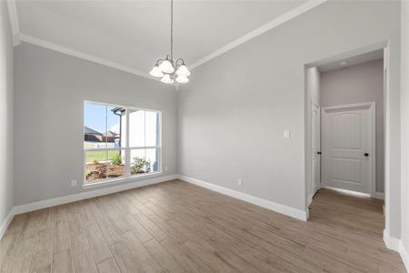 Unfurnished room with an inviting chandelier, crown molding, and light hardwood / wood-style floors