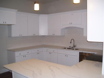 Kitchen with white cabinets, quartz countertops and tile backsplash