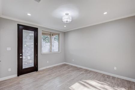 Spare room featuring crown molding and light wood-type flooring