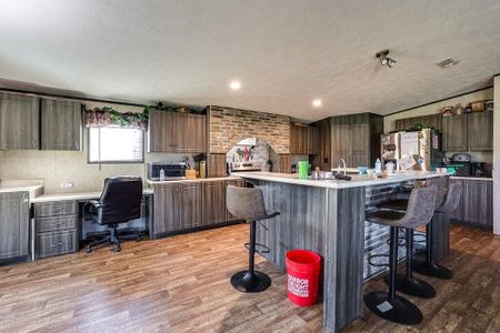 Kitchen featuring stainless steel refrigerator, light hardwood / wood-style floors, a kitchen island with sink, and a breakfast bar area