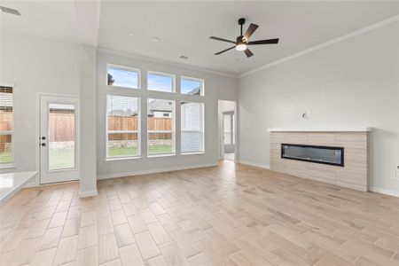 Unfurnished living room featuring ceiling fan, a tile fireplace, and ornamental molding