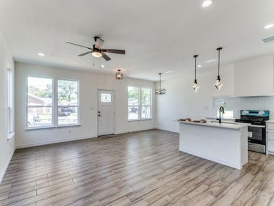 Kitchen with a healthy amount of sunlight, hanging light fixtures, stainless steel range, and white cabinets