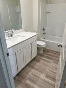 Full bathroom featuring shower / bathtub combination, vanity, toilet, and vinyl floors