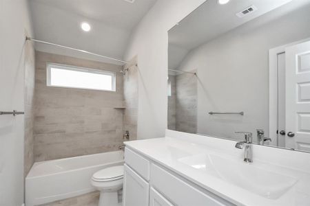 Secondary bath features tile flooring, bath/shower combo with tile surround, light stained wood cabinets, beautiful light countertop. Sample photo of similar plan. As-built color and selections may vary.