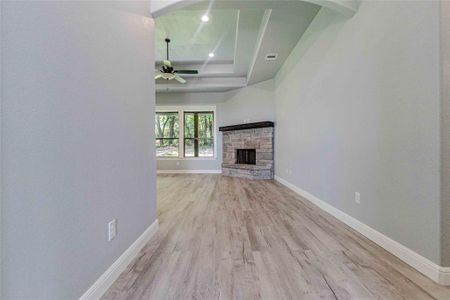 Unfurnished living room with a tray ceiling, ceiling fan, light hardwood / wood-style floors, and a fireplace