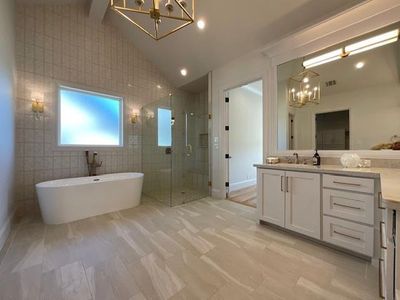 Bathroom with shower with separate bathtub, vaulted ceiling with beams, tile walls, vanity, and an inviting chandelier