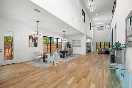 Dining room featuring a notable chandelier, light wood-type flooring, a high ceiling, and a healthy amount of sunlight