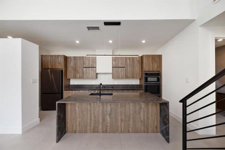 Chef's kitchen featuring waterfall natural stone countertops, Italian-inspired cabinetry