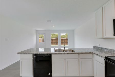 Kitchen featuring sink, light stone counters, white cabinetry, light tile patterned flooring, and dishwasher