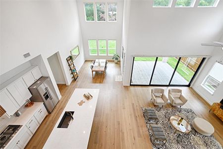 Living room with light hardwood / wood-style floors and a high ceiling