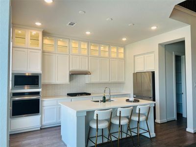 Kitchen with tile backsplash, quartz countertops, cooktop, new 4 door refrigerator with icemaker & built-in microwave and convection oven.