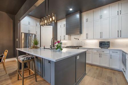 Kitchen featuring custom range hood, light hardwood / wood-style flooring, a center island with sink, and white cabinets