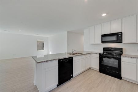 Kitchen featuring light wood-type flooring, black appliances, sink, and white cabinets