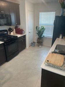 Kitchen with black appliances and light tile patterned flooring