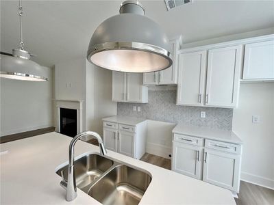 Kitchen featuring hanging light fixtures, light hardwood / wood-style floors, sink, and backsplash