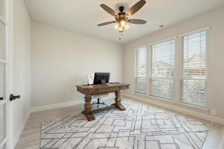 The Office/study with light engineered wood floors, ceiling fan & light kit has glass French doors and overlooks the front yard.