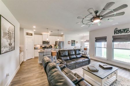 Living room with ceiling fan with notable chandelier and light hardwood / wood-style flooring