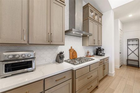 Sleek tile backsplash up the entire wall with a stainless steel vent hood.