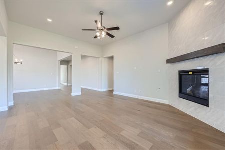 Unfurnished living room with hardwood / wood-style floors, ceiling fan, and a high end fireplace