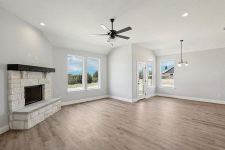 Unfurnished living room featuring a fireplace, ceiling fan, hardwood / wood-style floors, and lofted ceiling