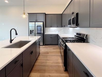 Modern Chef's Kitchen: Sleek cabinetry and stainless-steel appliances set against a marble backsplash, with ample counter space and warm wood flooring.