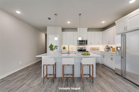 Kitchen with sink, decorative light fixtures, white cabinetry, appliances with stainless steel finishes, and light wood-type flooring